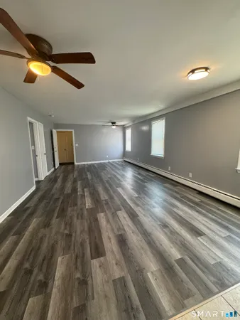 a view of a big room with wooden floor ceiling fan and windows