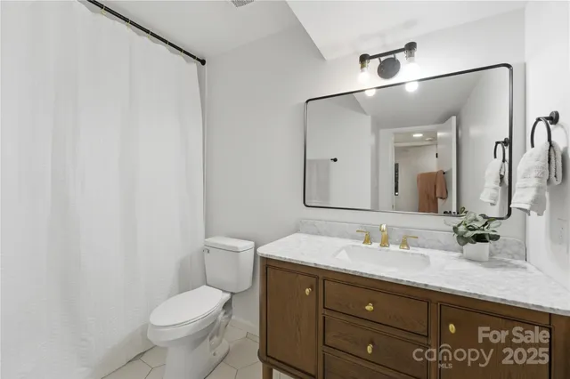 a bathroom with a granite countertop sink toilet and mirror
