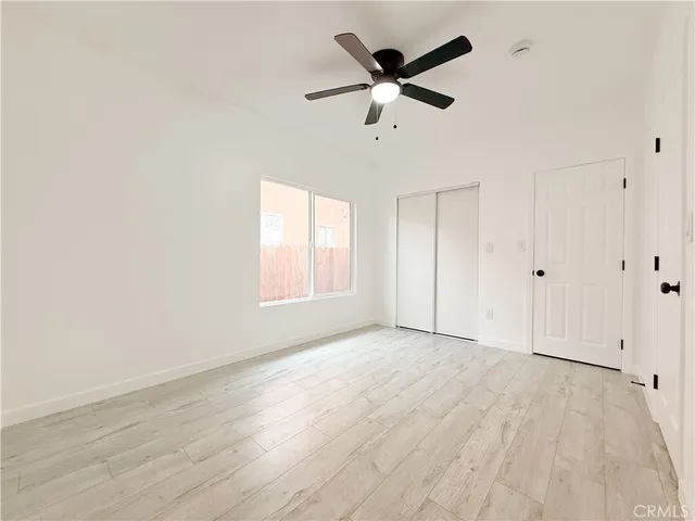 an empty room with wooden floor fan and windows