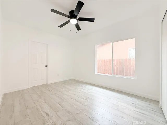 an empty room with wooden floor fan and windows