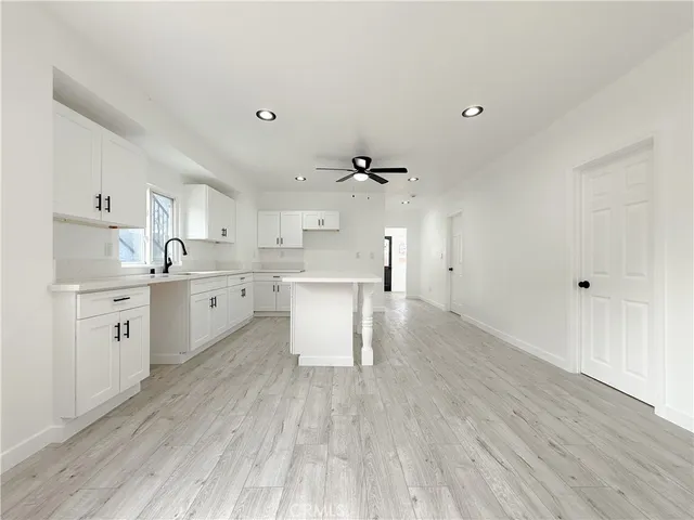 a large white kitchen with kitchen island a sink stainless steel appliances and cabinets