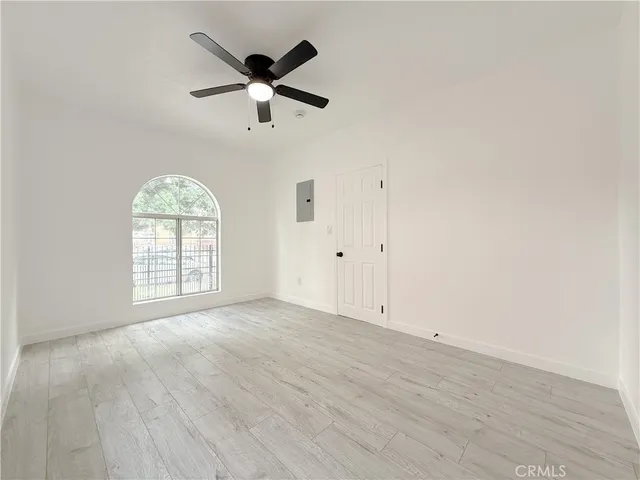 an empty room with wooden floor fan and windows