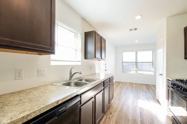 a kitchen with granite countertop a sink a stove cabinets and wooden floor