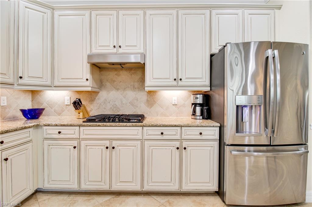 2930 Aviamar Circle Naples, FL 34114 - Photo 13 of 39 Kitchen featuring stainless steel fridge, black gas stovetop, under cabinet range hood, backsplash, and light stone countertops