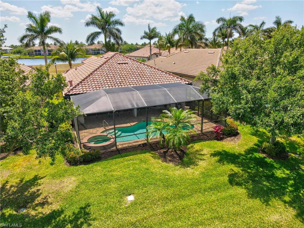 2930 Aviamar Circle Naples, FL 34114 - Photo 33 of 39 View of pool with a water view, a pool with connected hot tub, glass enclosure, a patio, and a yard