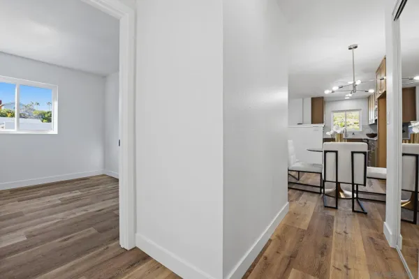 a view of a hallway with wooden floor and a bathroom