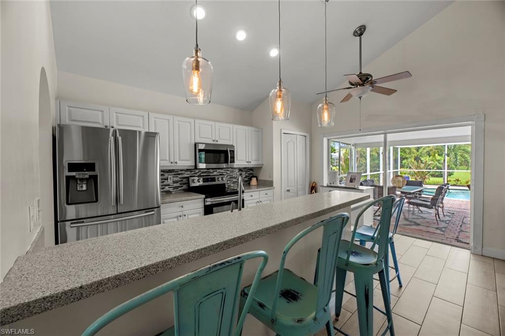 21778 Brixham Run Loop Estero, FL 33928 - Photo 12 of 48 a kitchen with stainless steel appliances a table chairs refrigerator and microwave