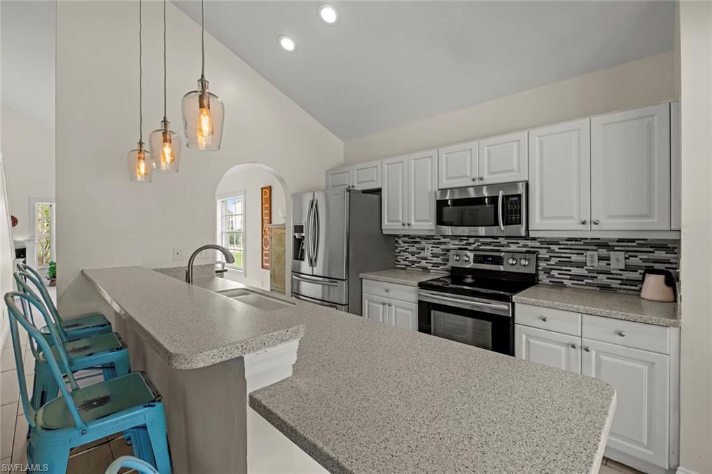 21778 Brixham Run Loop Estero, FL 33928 - Photo 8 of 48 a kitchen with stainless steel appliances granite countertop a stove a sink a microwave a refrigerator and white cabinets