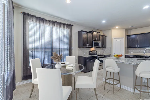 a living room with stainless steel appliances a dining table chair and a refrigerator