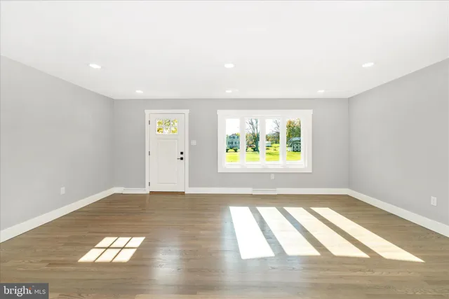 a view of an empty room with window and wooden floor
