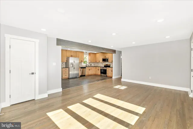 a kitchen with stainless steel appliances granite countertop a stove a sink dishwasher a refrigerator and white cabinets with wooden floor