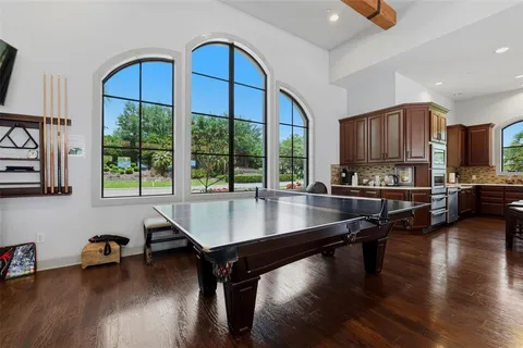 a room with furniture pool table wooden floor and a window