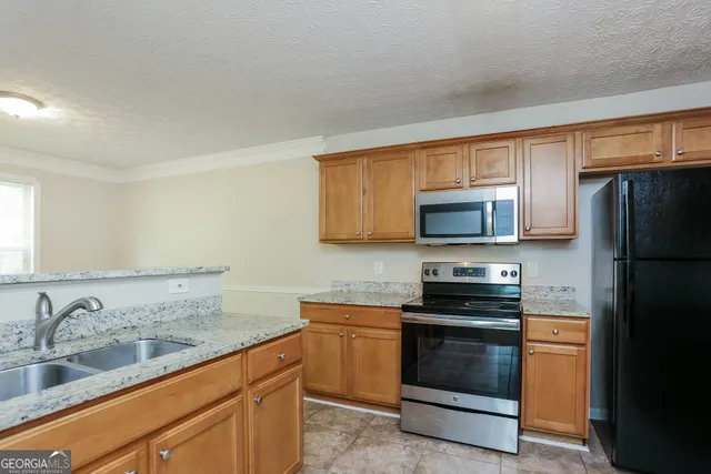 a kitchen with stainless steel appliances granite countertop a refrigerator stove and sink