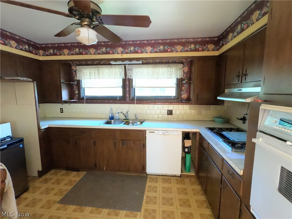 1425 Eastern Road Rittman, OH 44270 - Photo 12 of 28 Kitchen featuring white dishwasher, dark brown cabinets, backsplash, oven, and sink