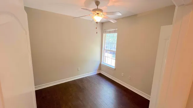 an empty room with a window and a chandelier fan