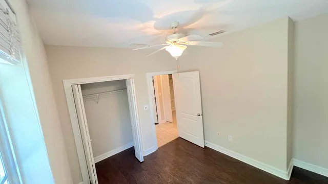 an empty room with wooden floor and ceiling fan