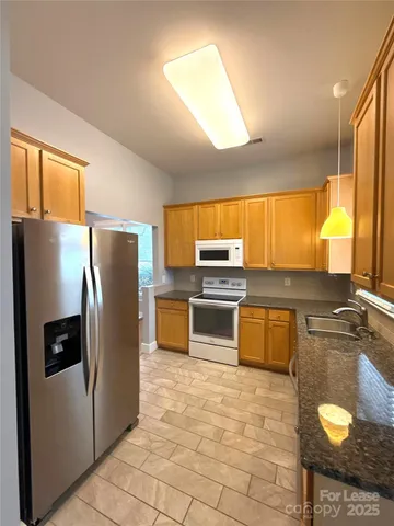 a kitchen with stainless steel appliances granite countertop a refrigerator a stove a sink and dishwasher