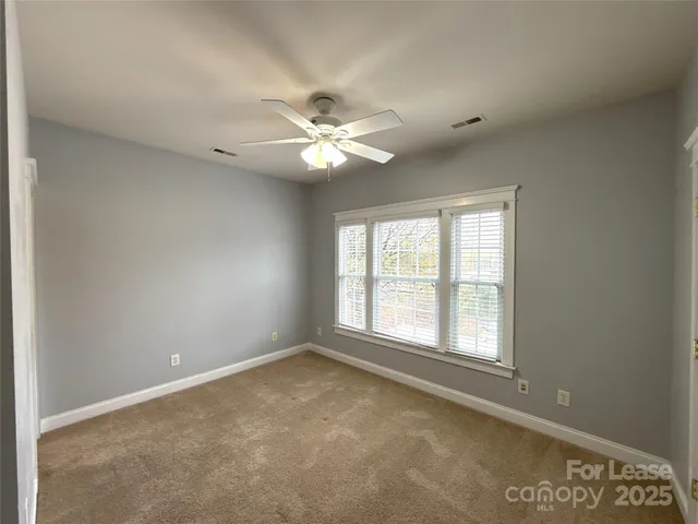 an empty room with windows and ceiling fan