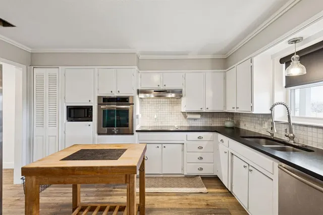 a kitchen with granite countertop white cabinets and stainless steel appliances