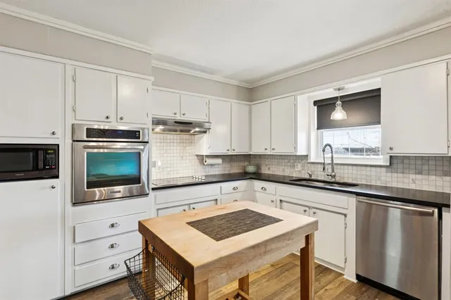 a kitchen with granite countertop a sink stove and microwave