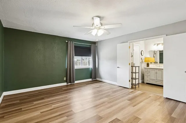 a view of empty room with wooden floor and ceiling fan