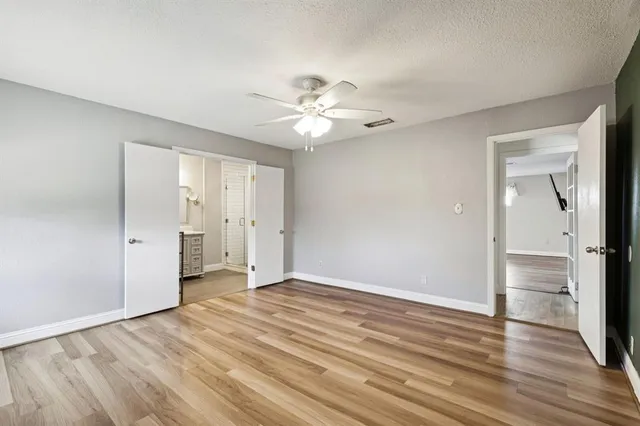 a view of an empty room and wooden floor cabinet and a ceiling fan