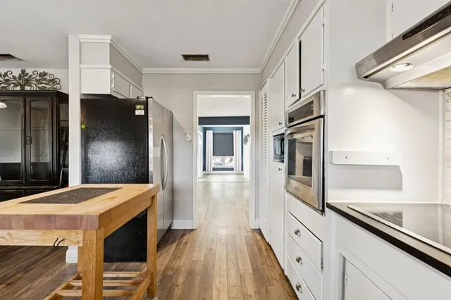 a kitchen with stainless steel appliances granite countertop a refrigerator a stove and a sink with wooden floor