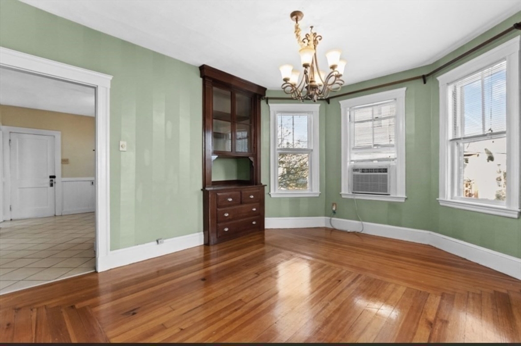 141 4th Street Medford, MA 02155 - Photo 13 of 26 an empty room with wooden floor chandelier and windows