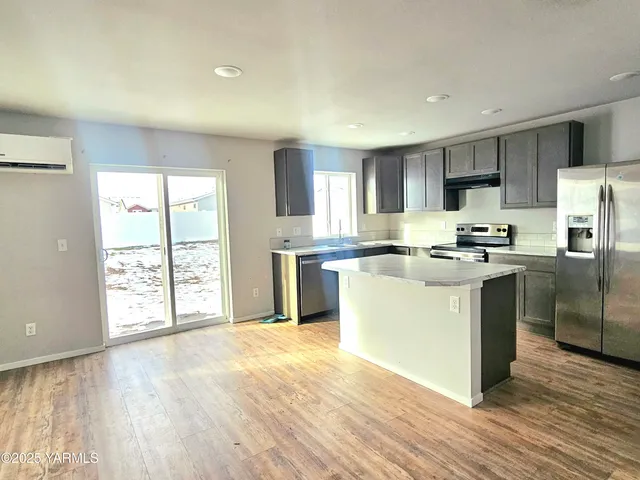 a kitchen with stainless steel appliances granite countertop a refrigerator a stove top oven a sink and dishwasher with wooden floor