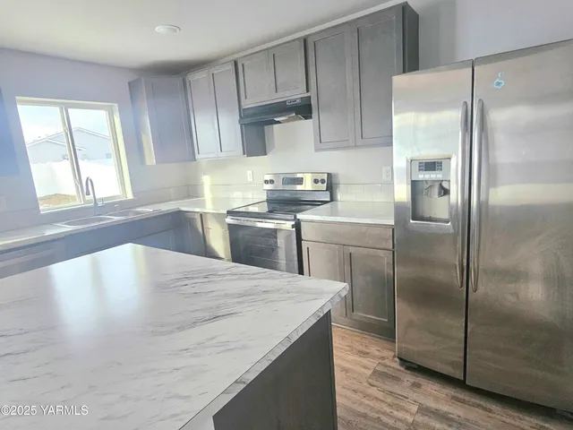 a kitchen with stainless steel appliances granite countertop a refrigerator a sink a stove and cabinets