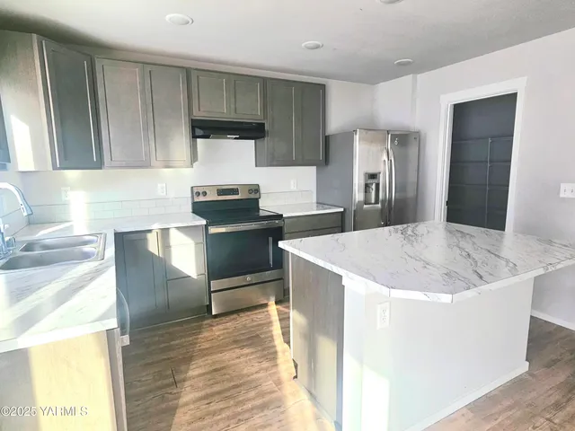 a kitchen with stainless steel appliances granite countertop a sink stove and refrigerator