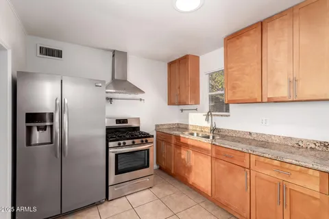 a kitchen with stainless steel appliances granite countertop a stove a sink and a refrigerator