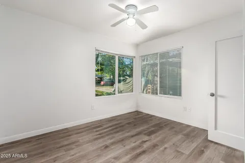 a view of empty room with wooden floor and fan
