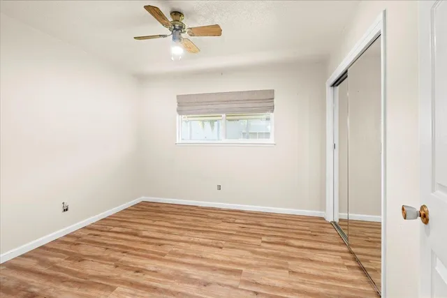 a view of a room with wooden floor and a ceiling fan