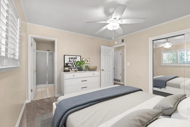 a bedroom with a bed chandelier dresser and a window