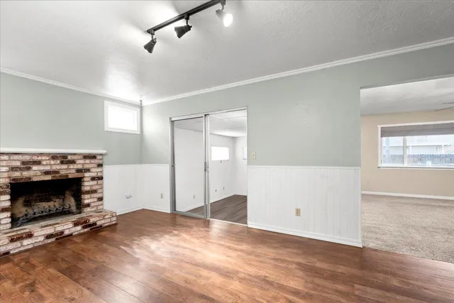 an empty room with wooden floor fireplace and windows