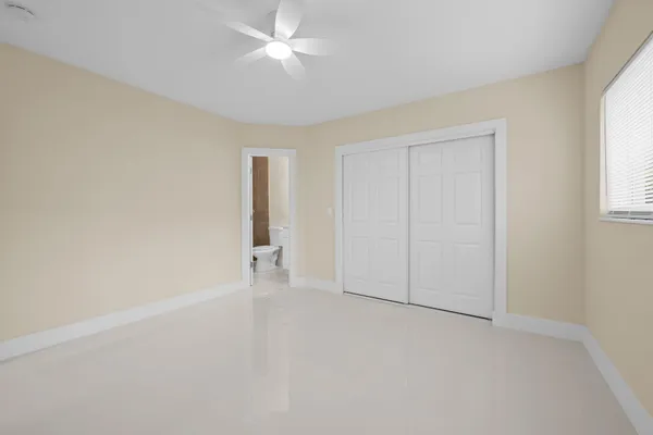 an empty room with a ceiling fan and a window
