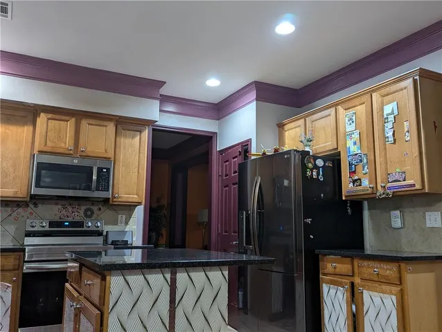 a kitchen with stainless steel appliances granite countertop a refrigerator and a stove top oven