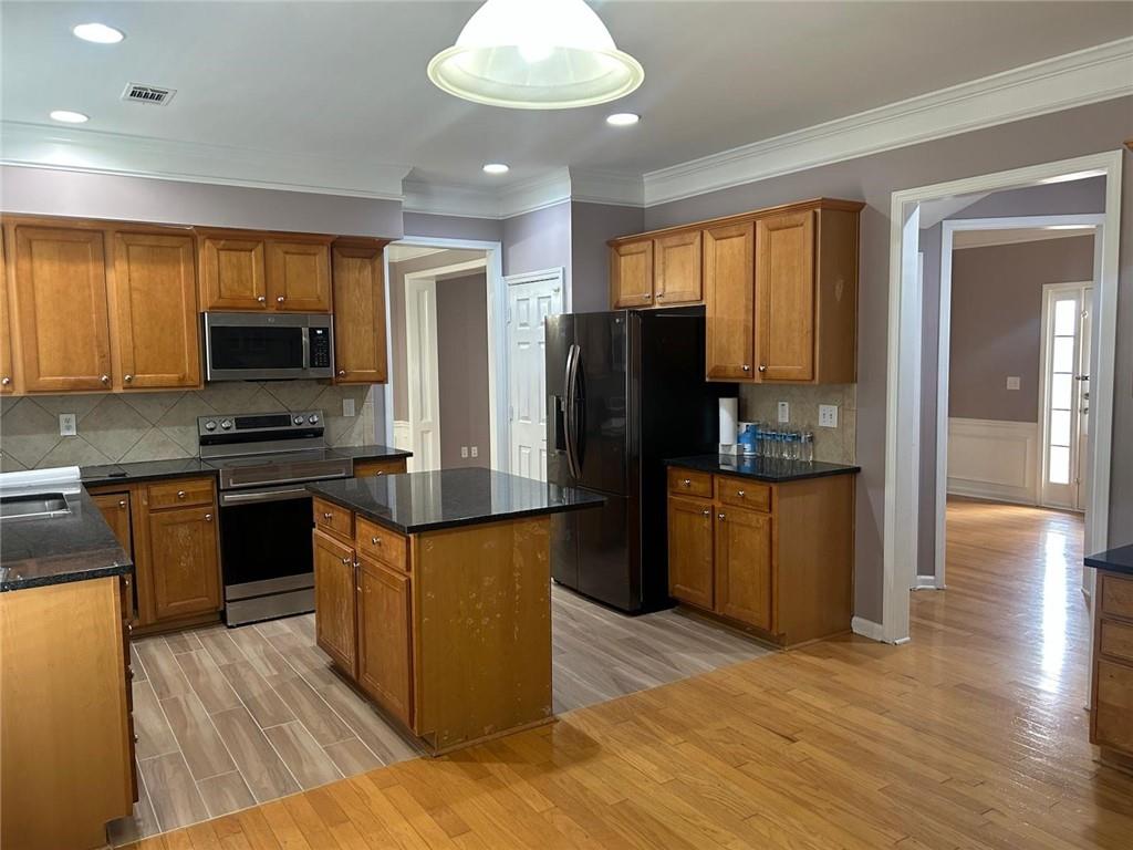 815 Earlham Drive Suwanee, GA 30024 - Photo 8 of 30 a kitchen with granite countertop wooden floors a stove and a refrigerator