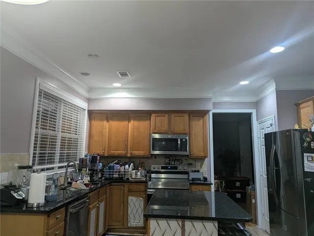 a kitchen with kitchen island granite countertop a sink stove and refrigerator