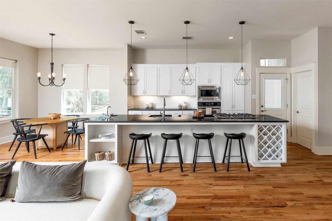 a large kitchen with granite countertop a stove a sink a dining table and chairs