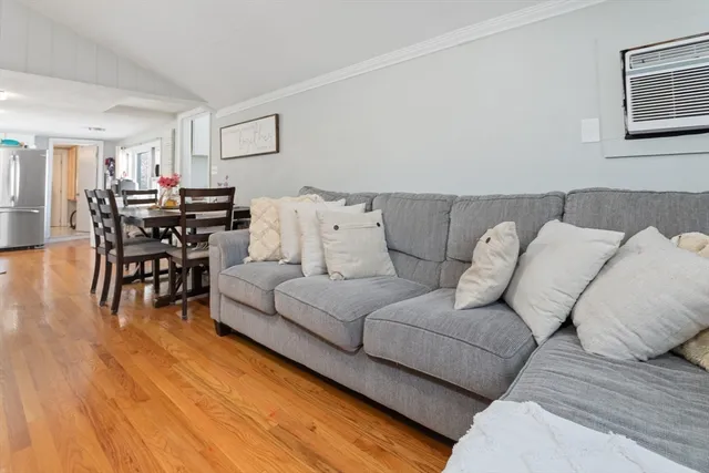a living room with furniture and a dining table with wooden floor
