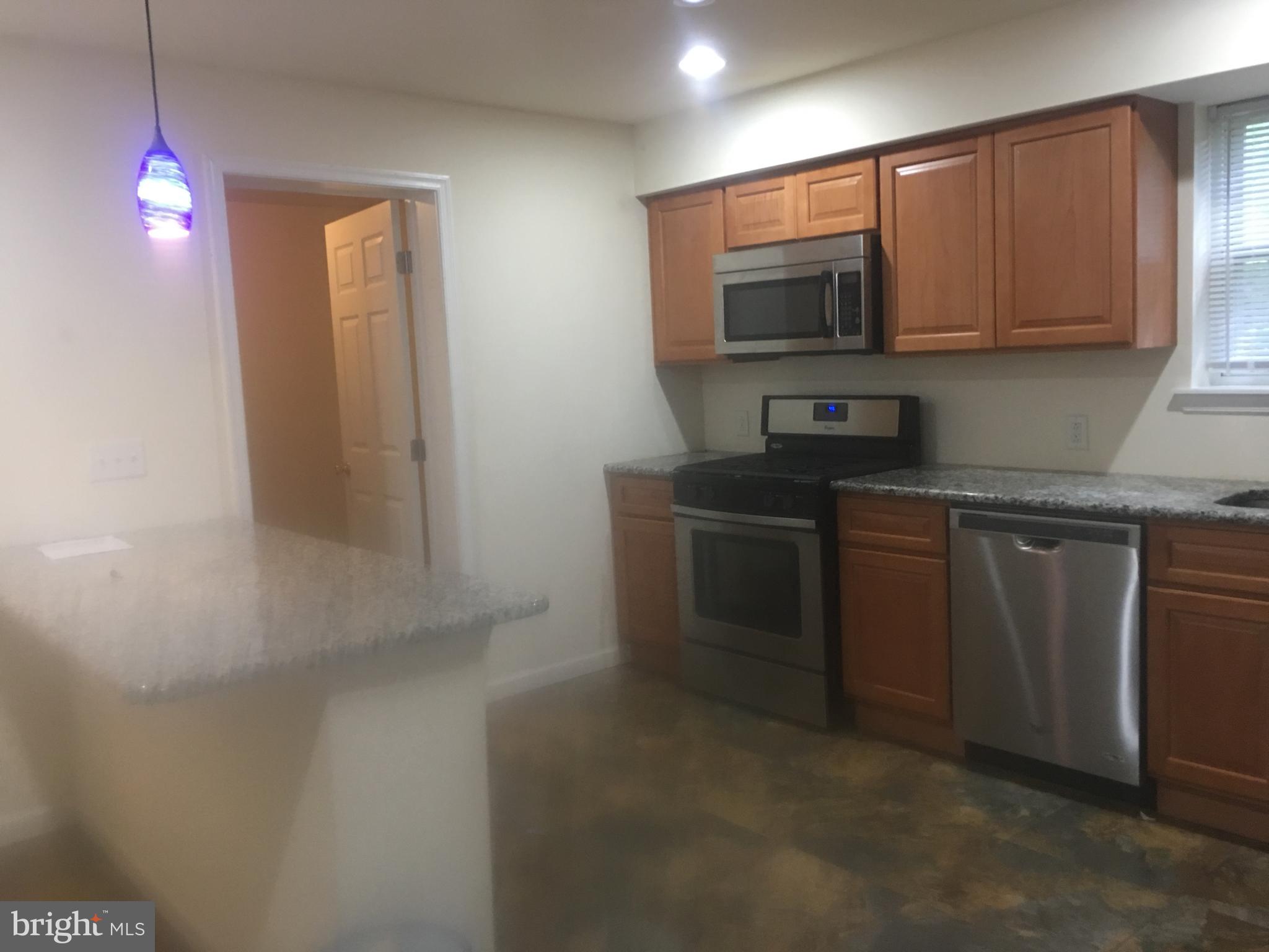25 Zane Street, Unit A Glassboro, NJ 08028 - Photo 3 of 16 a kitchen with stainless steel appliances granite countertop a sink a stove and microwave