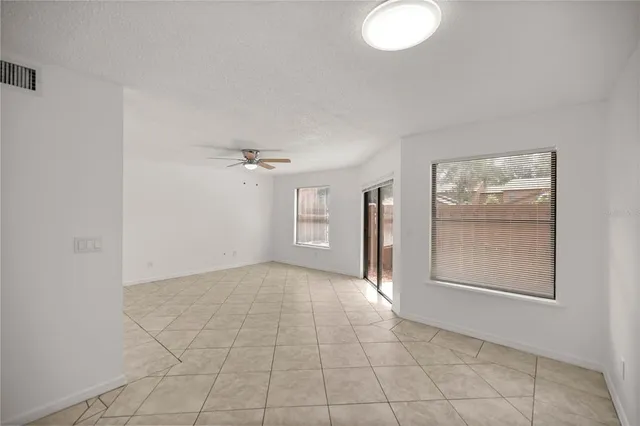 an empty room with windows and fan