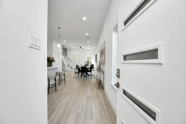 a kitchen with stainless steel appliances a sink a stove a refrigerator and white cabinets with wooden floor