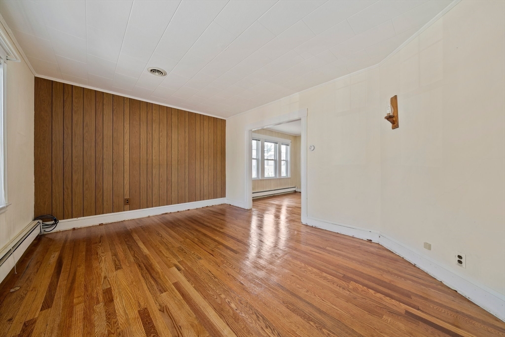 12 Cotuit Street Boston, MA 02132 - Photo 4 of 19 a view of an empty room with wooden floor and a window