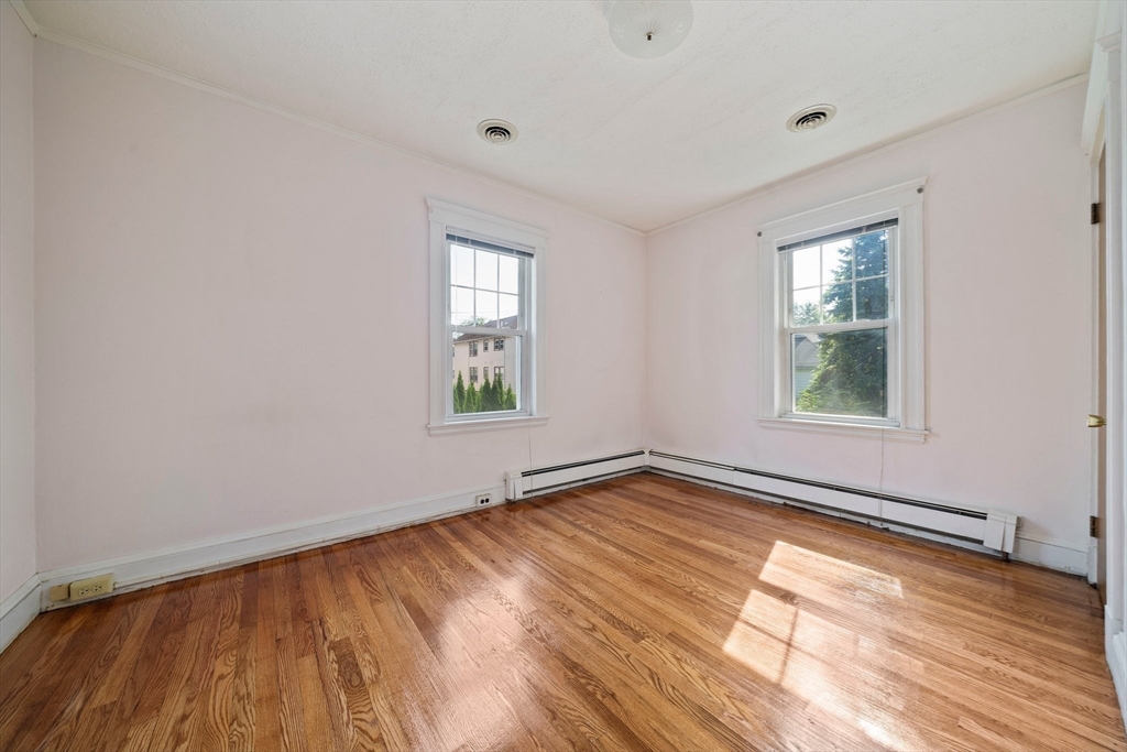 12 Cotuit Street Boston, MA 02132 - Photo 9 of 19 an empty room with wooden floor and windows