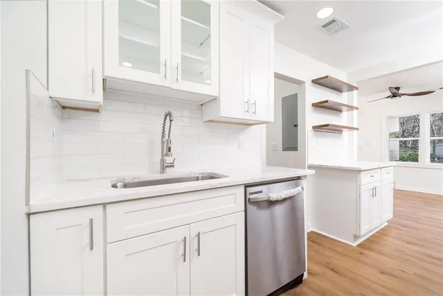 a kitchen with stainless steel appliances granite countertop a sink a stove and white cabinets with wooden floor