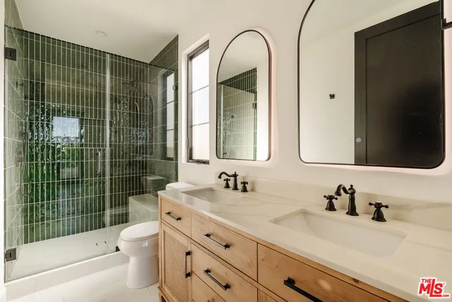 a bathroom with a granite countertop sink a toilet a mirror and shower