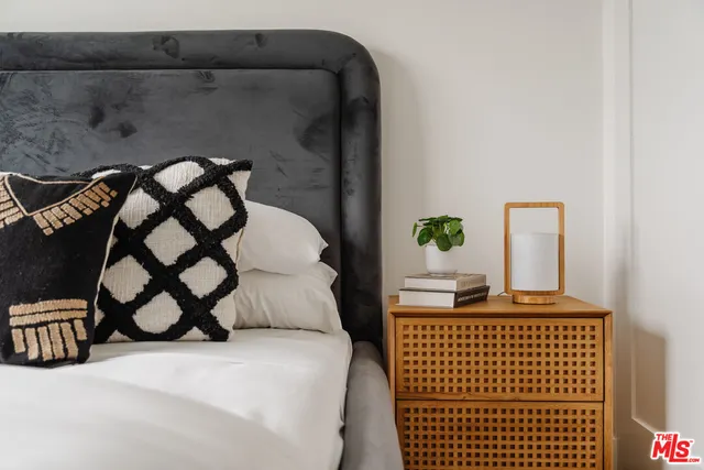 a bedroom with a bed next to a window with potted plants